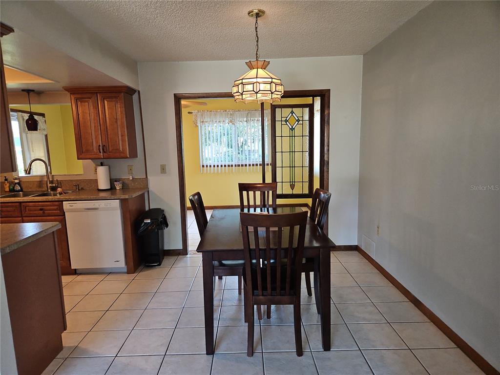 A dining area with a wooden table, chairs, tile flooring, and a stained glass window — 11087 SW 77TH COURT, OCALA, FL