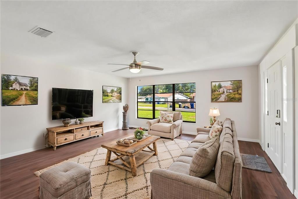 A living room features wood-look flooring, a beige sofa, a coffee table, and large windows — 4545 DEBBIE LANE, LUTZ, FL