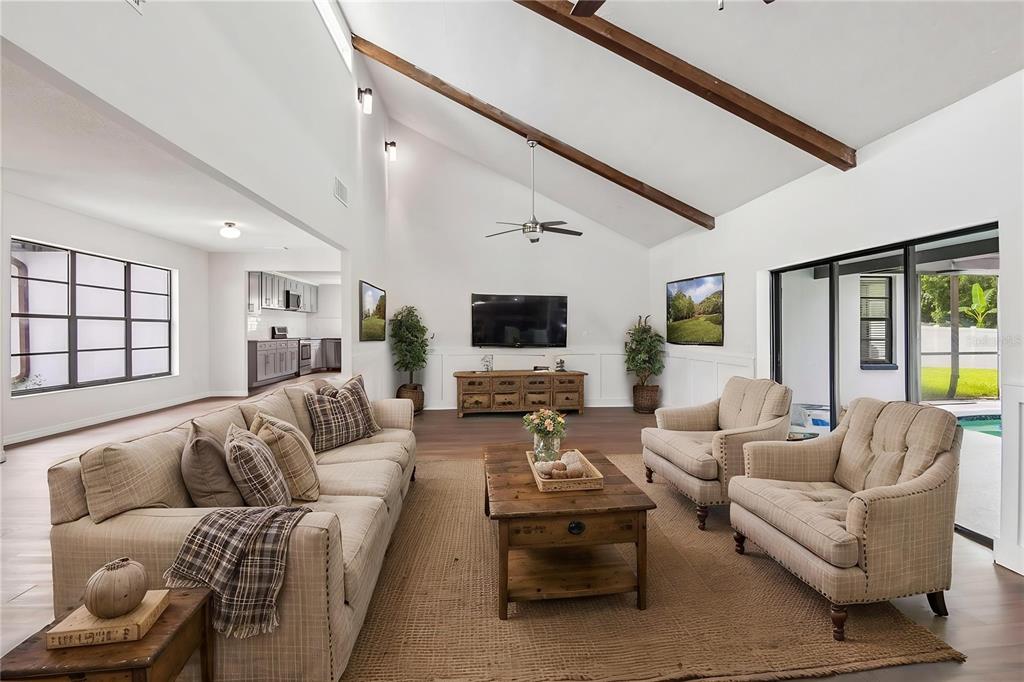 A living room features vaulted ceilings with exposed wooden beams, a fireplace, and neutral furniture — 4545 DEBBIE LANE, LUTZ, FL