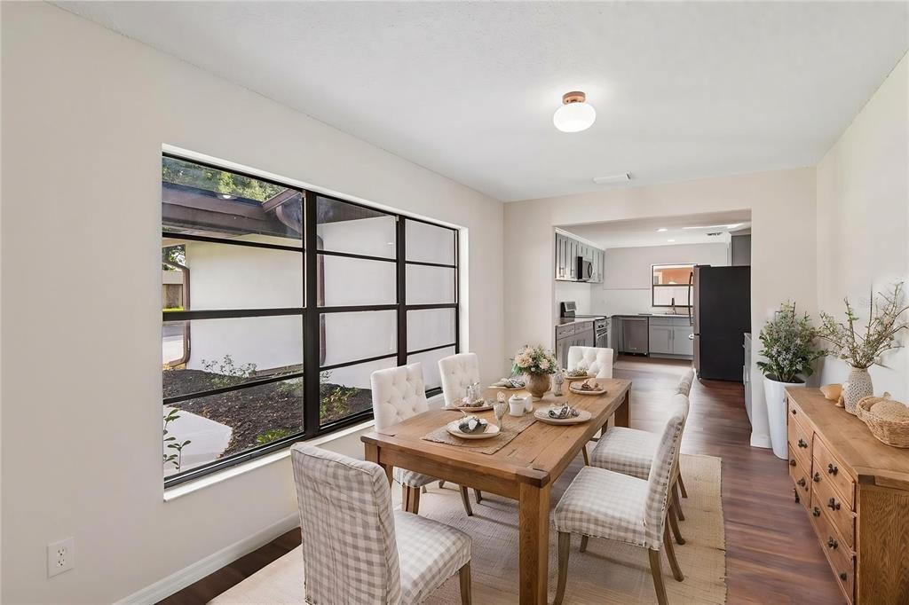 A dining room with a wooden table, checkered chairs, and a large window overlooking landscaping — 4545 DEBBIE LANE, LUTZ, FL