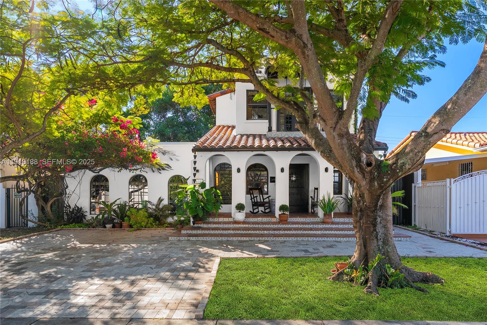 A two-story Spanish-style house features arched entryways, a tiled porch, and a large front tree — 1650 SW 16th St, Miami FL 33145, MIAMI, FL