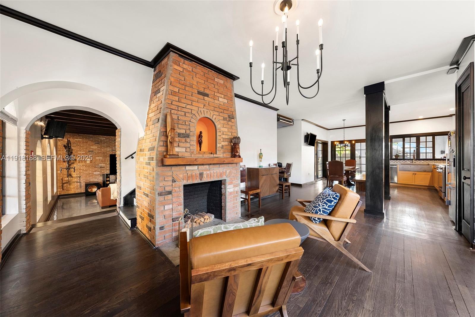 A living room features a central brick fireplace, dark wood floors, and a chandelier — 1650 SW 16th St, Miami FL 33145, MIAMI, FL