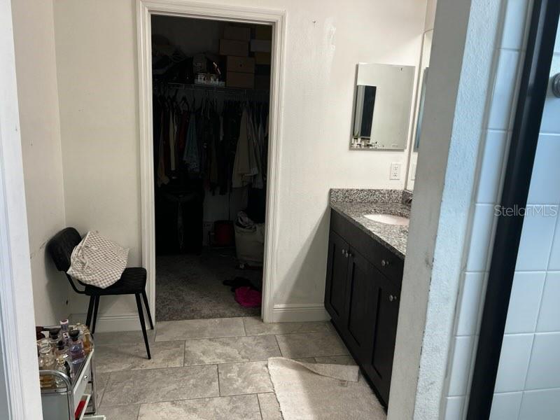 A bathroom with a dark vanity, granite countertop, and an adjacent walk-in closet — 3516 WOODMONT DRIVE, PARRISH, FL