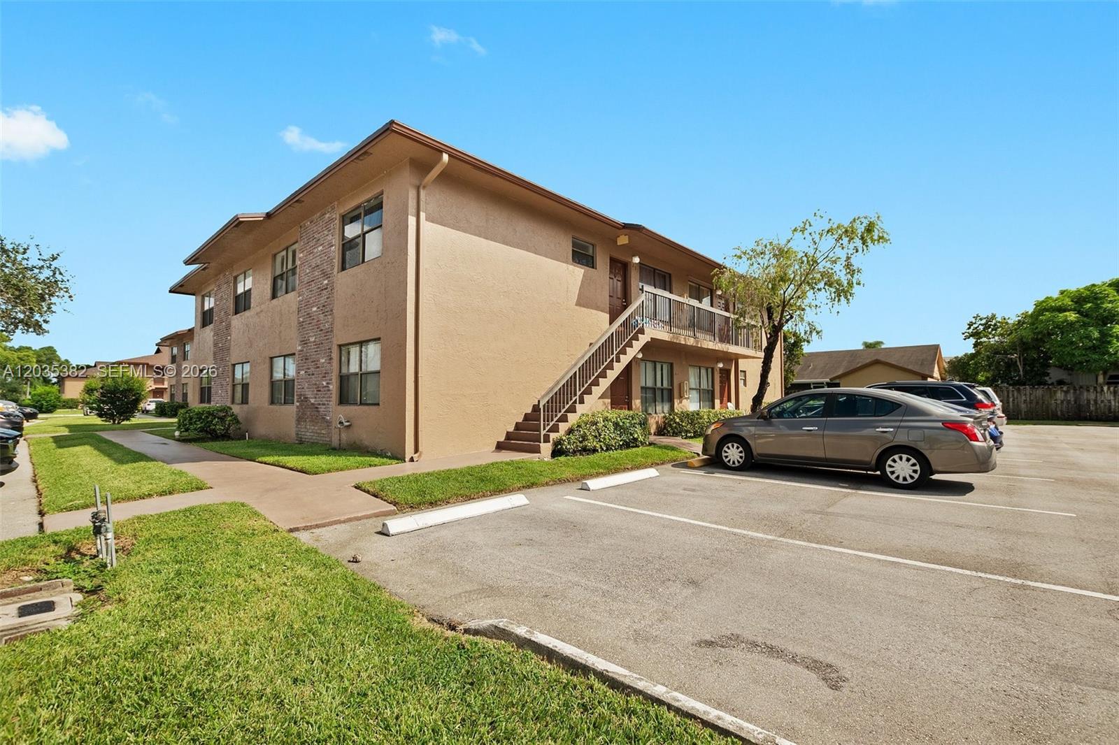 A two-story apartment building with exterior stairs and a parking lot in front — 10053 Winding Lake Rd # 101, Sunrise FL 33351, SUNRISE, FL