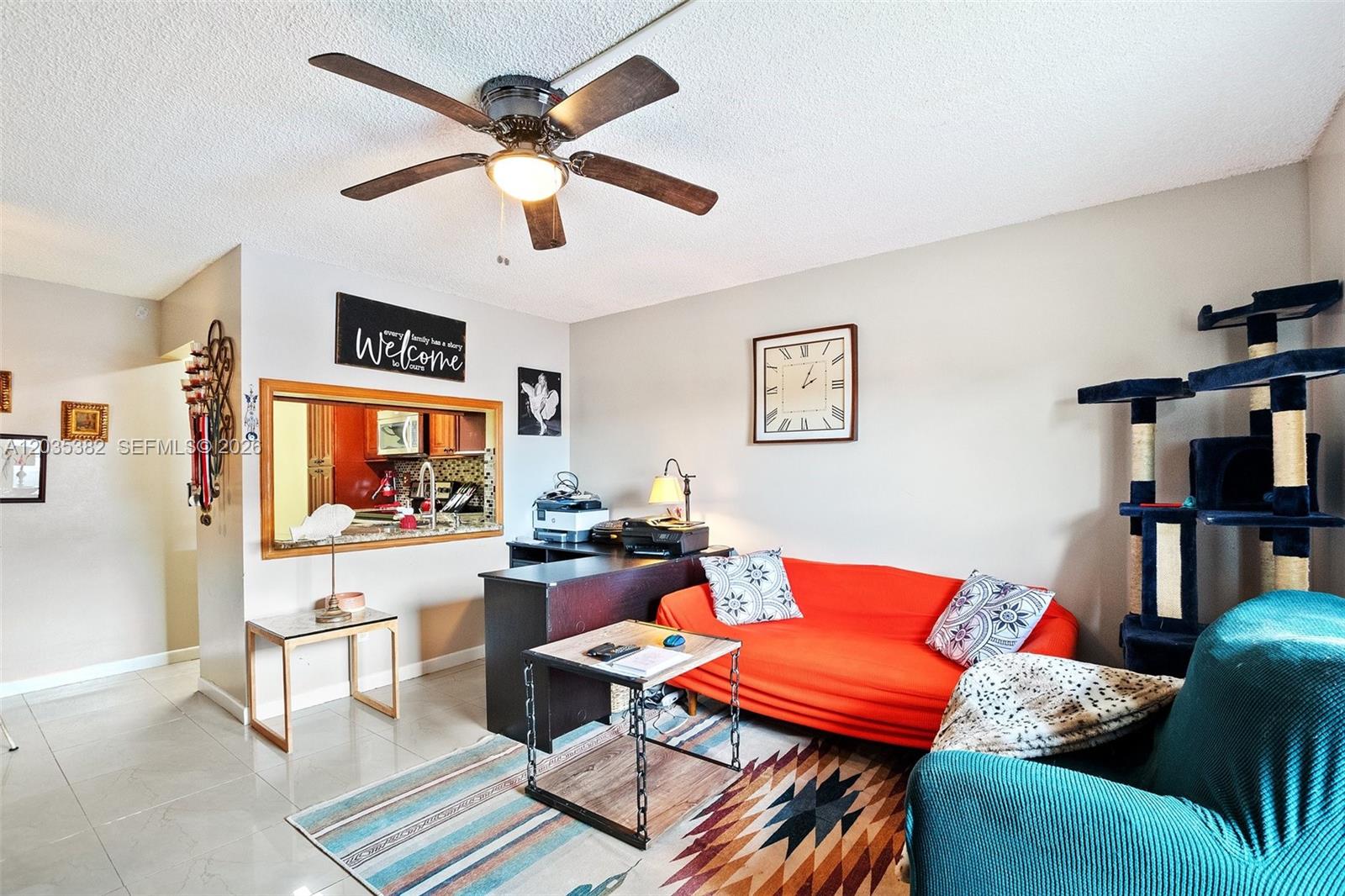 A living room features an orange sofa, a desk, a cat tree, and a ceiling fan — 10053 Winding Lake Rd # 101, Sunrise FL 33351, SUNRISE, FL