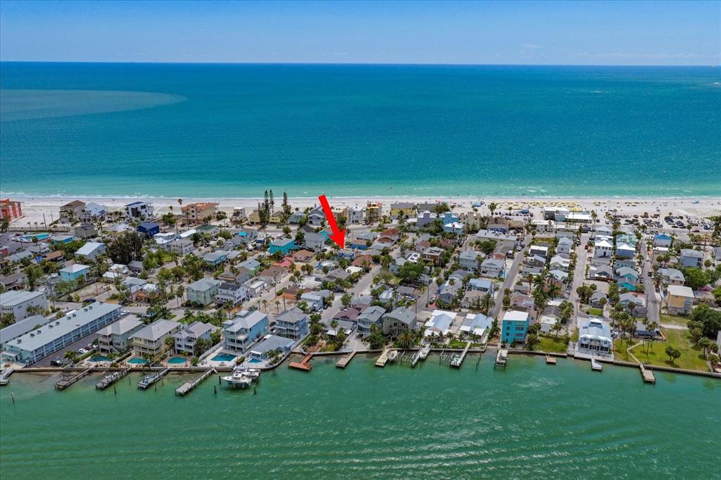 An aerial view shows a coastal neighborhood with houses, a beach, and a bay — 122 87TH AVENUE, TREASURE ISLAND, FL