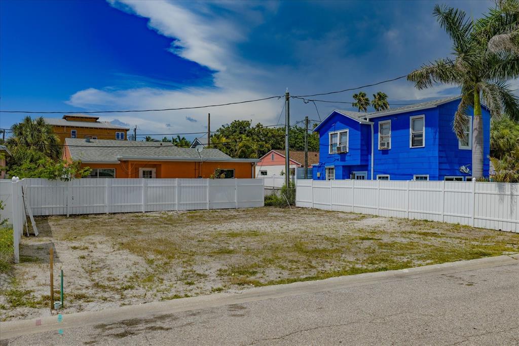 A vacant, fenced-in residential lot sits between an orange house and a blue house — 122 87TH AVENUE, TREASURE ISLAND, FL