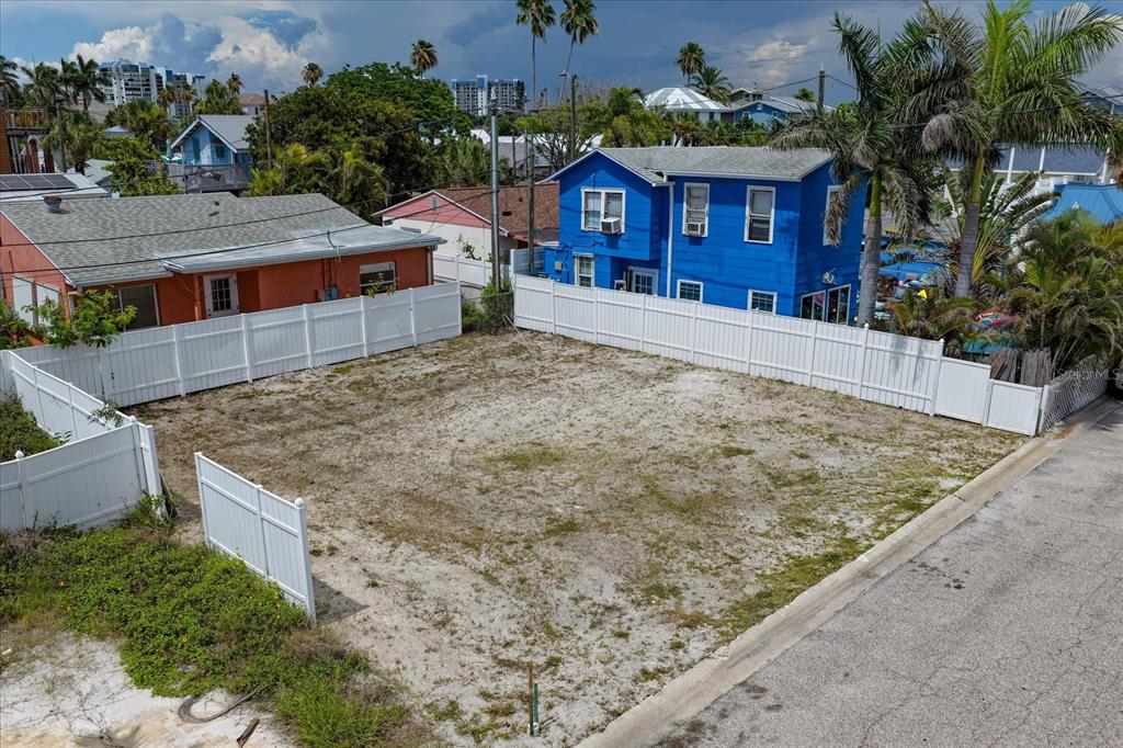An elevated view of a vacant, fenced-in residential lot situated between two houses — 122 87TH AVENUE, TREASURE ISLAND, FL