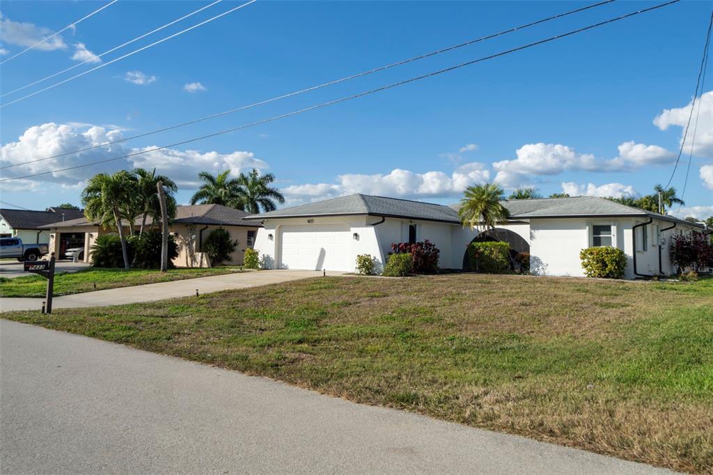 A single-story white house with a two-car garage sits on a grassy lot — 1433 SE 28TH TERRACE, CAPE CORAL, FL