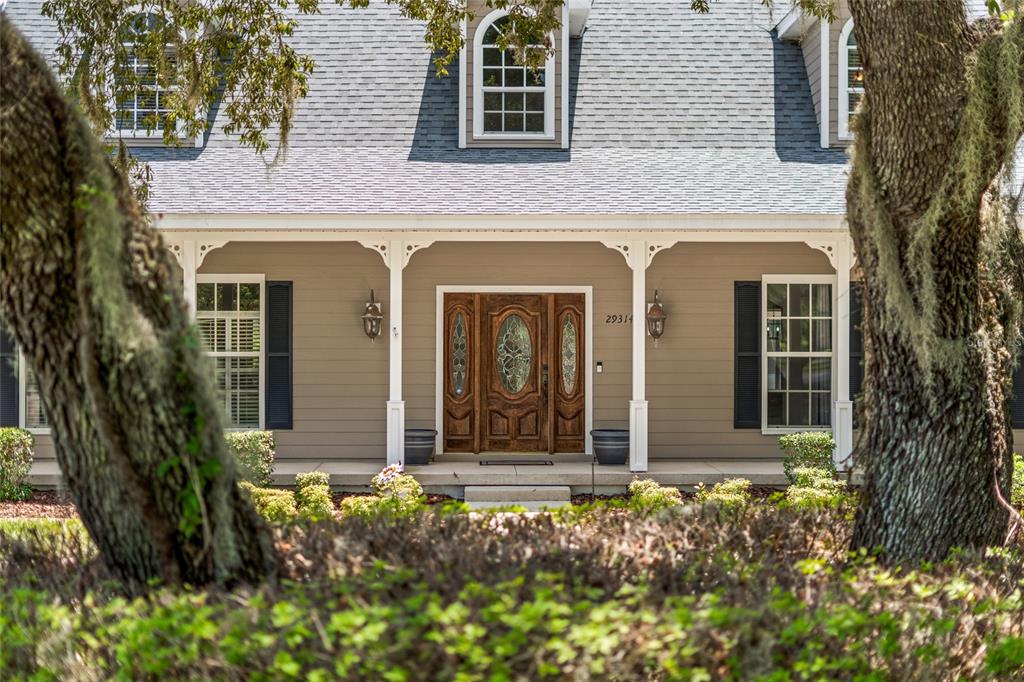 A tan house with a covered porch, wooden front door, and dormer windows — 29314 W OLD MILL, TAVARES, FL