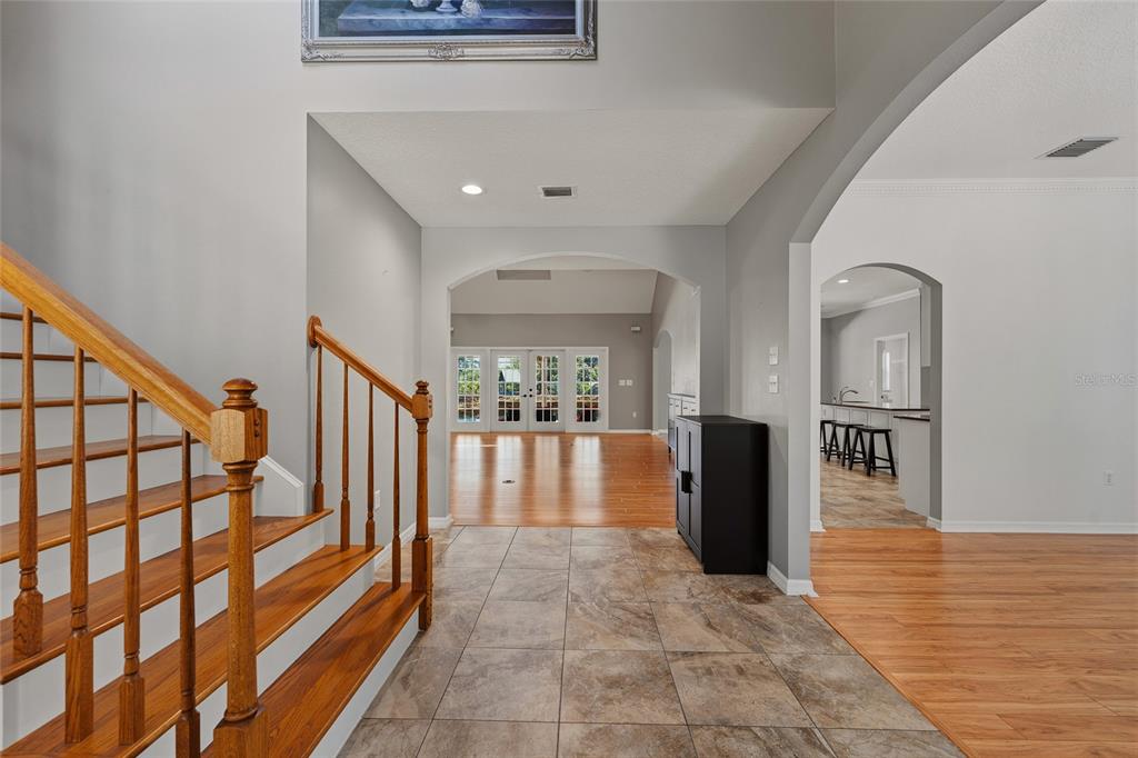An entryway with tile flooring, a wooden staircase, and an arched opening to a living area — 29314 W OLD MILL, TAVARES, FL