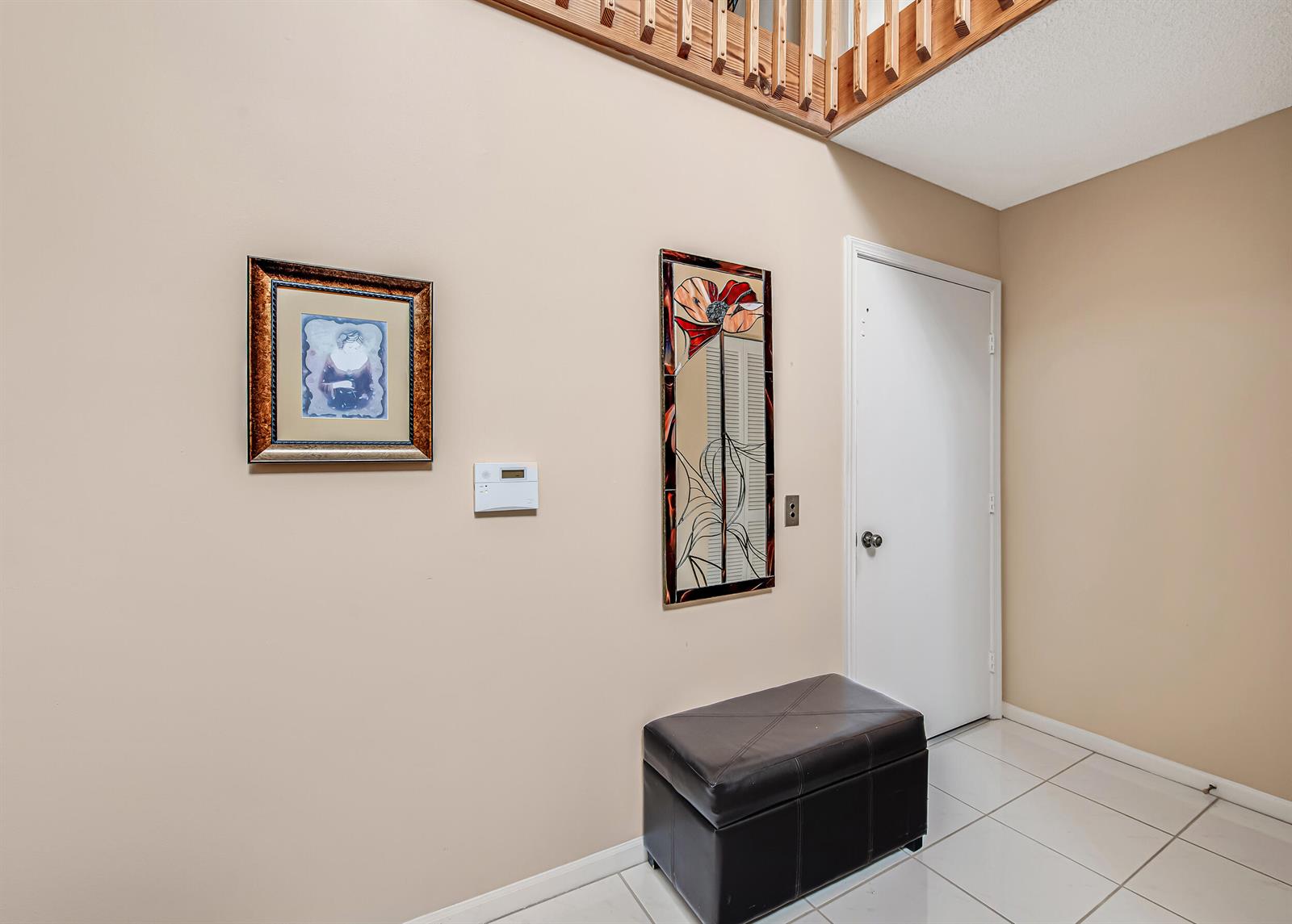 An entryway features a dark leather ottoman, two wall hangings, and a white door — 7384 Lake Meadow Way # 201, Boynton Beach FL 33437, BOYNTON BEACH, FL