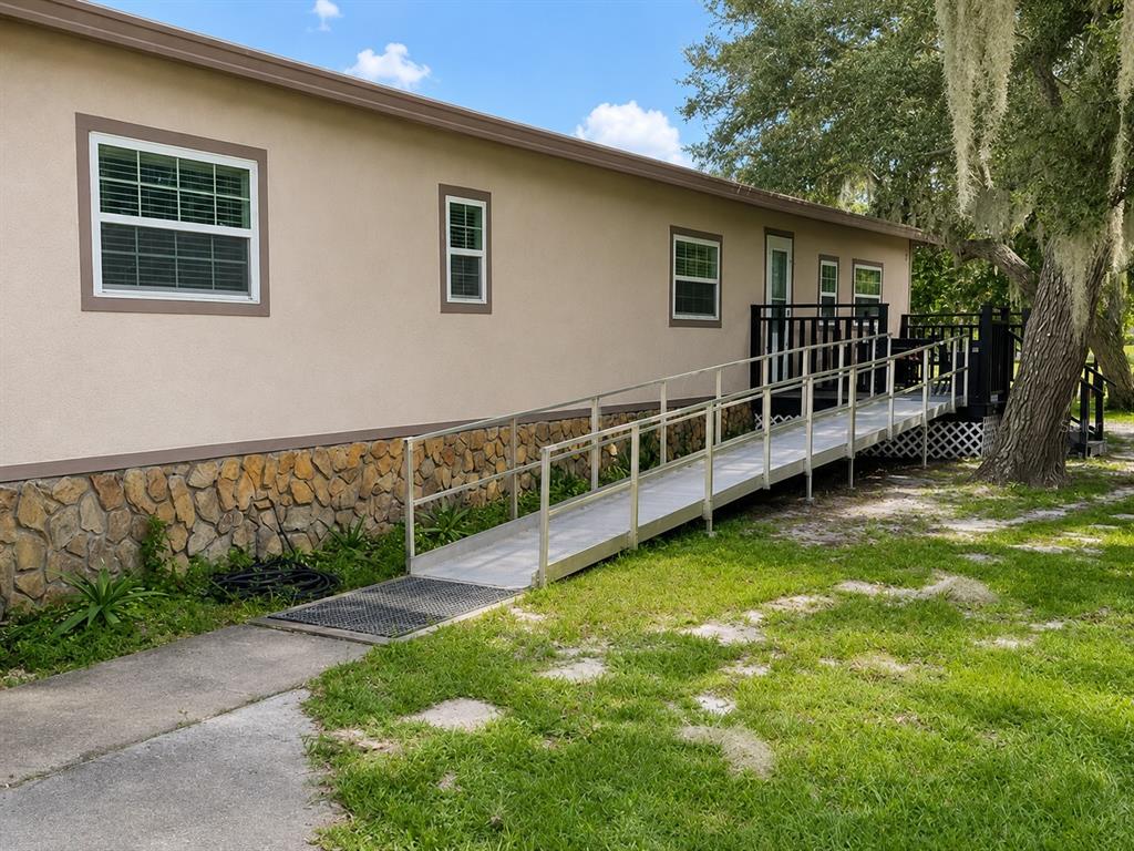 An exterior view of a house with a metal wheelchair ramp leading to a deck — 15355 SW 85 AVENUE, DUNNELLON, FL