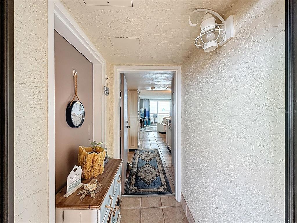 A hallway with textured walls leads to an interior room with tile flooring and decor — 6009 SEA RANCH DRIVE UNIT 608, HUDSON, FL