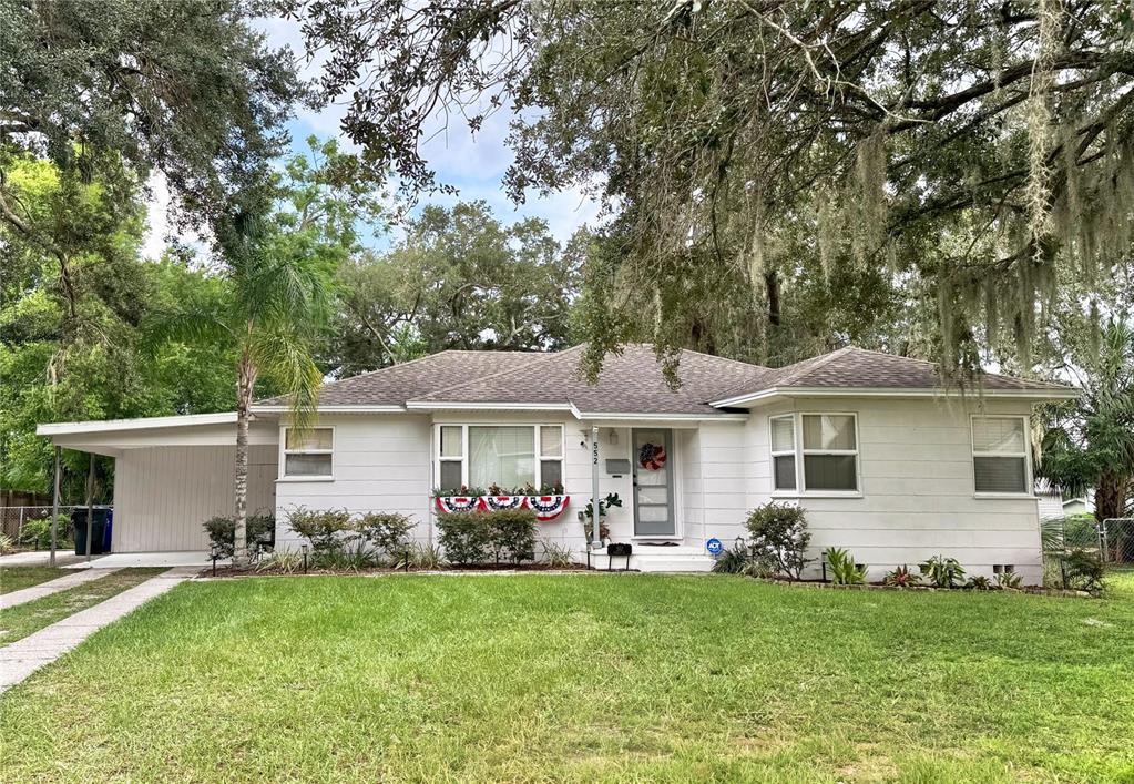 A single-story white house with a carport, a front lawn, and mature oak trees — 552 PALENCIA PLACE, LAKELAND, FL