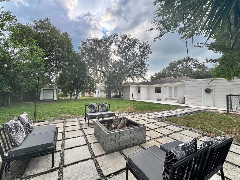 A white house sits behind a large tree with a stone-bordered garden bed — 552 PALENCIA PLACE, LAKELAND, FL