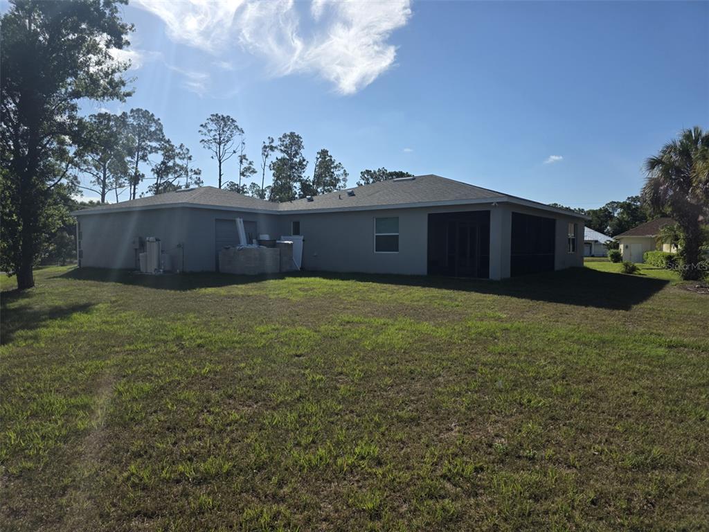 A view of the rear exterior of a single-story house with a screened-in porch — 1259 KAAYAN STREET, NORTH PORT, FL