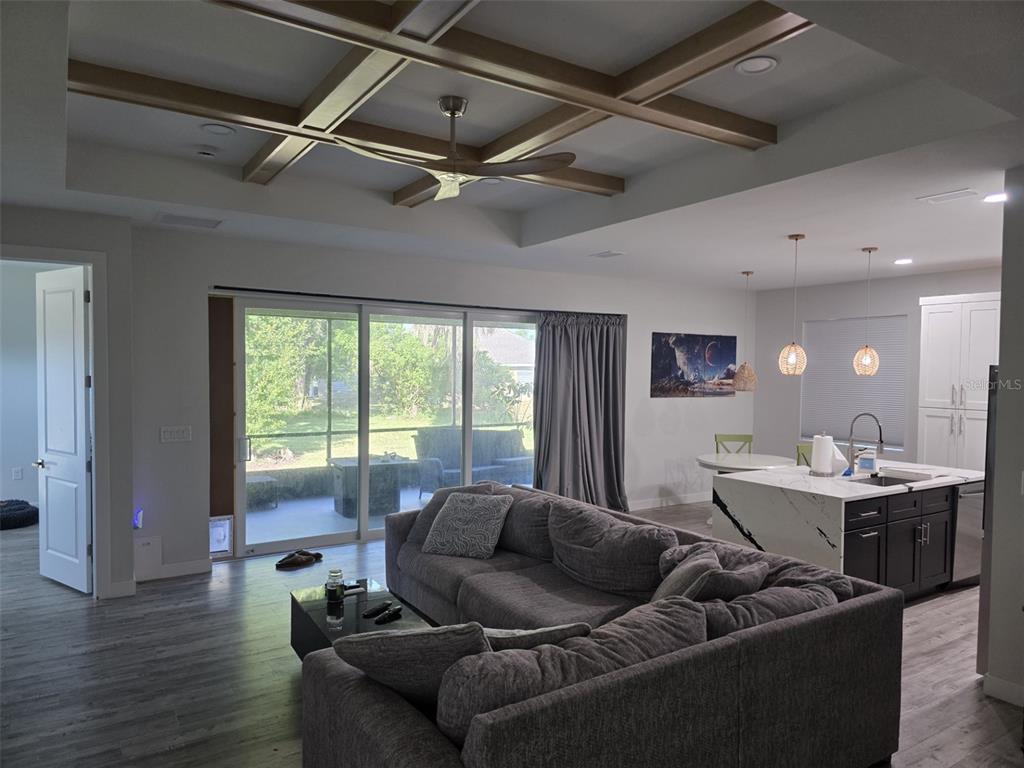 A living room with a coffered ceiling, gray sectional sofa, and sliding glass doors to a patio — 1259 KAAYAN STREET, NORTH PORT, FL