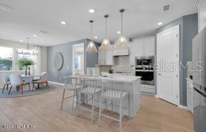 A kitchen with a white island, bar stools, and pendant lights next to a dining area — 345 FISHTAIL PLACE, PALM COAST, FL