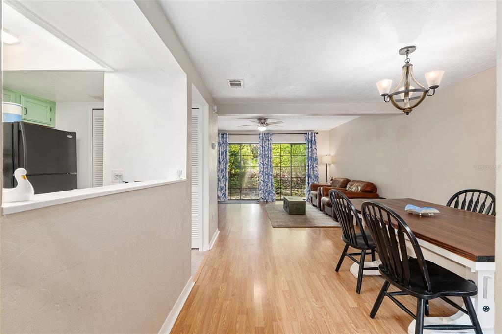 A dining area with a wooden table and chairs opens into a living room beyond — 900 SW 62ND BOULEVARD UNIT D24, GAINESVILLE, FL