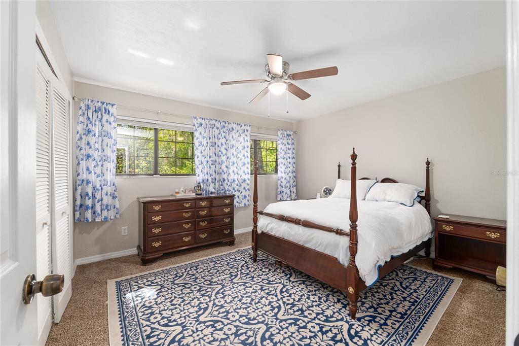 A bedroom features a four-poster bed, a wooden dresser, blue patterned curtains, and a rug — 900 SW 62ND BOULEVARD UNIT D24, GAINESVILLE, FL