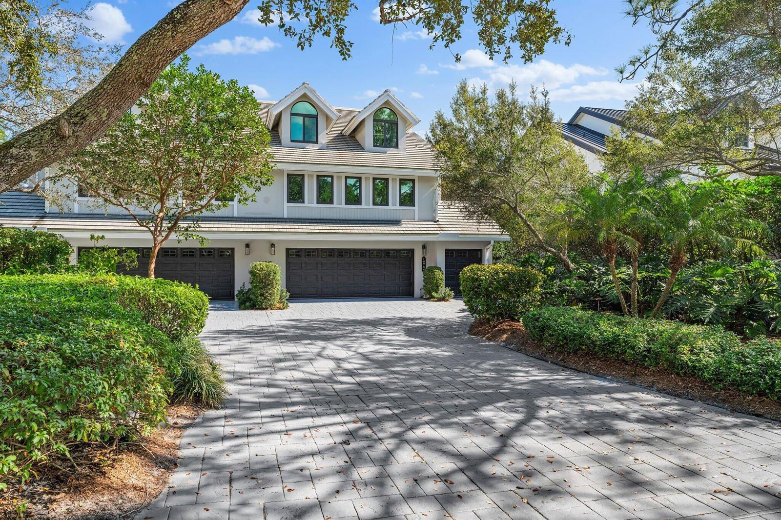 A multi-story house with a paved driveway, three garage doors, and dormer windows — 18760 SE Pineneedle Lane, Jupiter FL 33469, JUPITER, FL