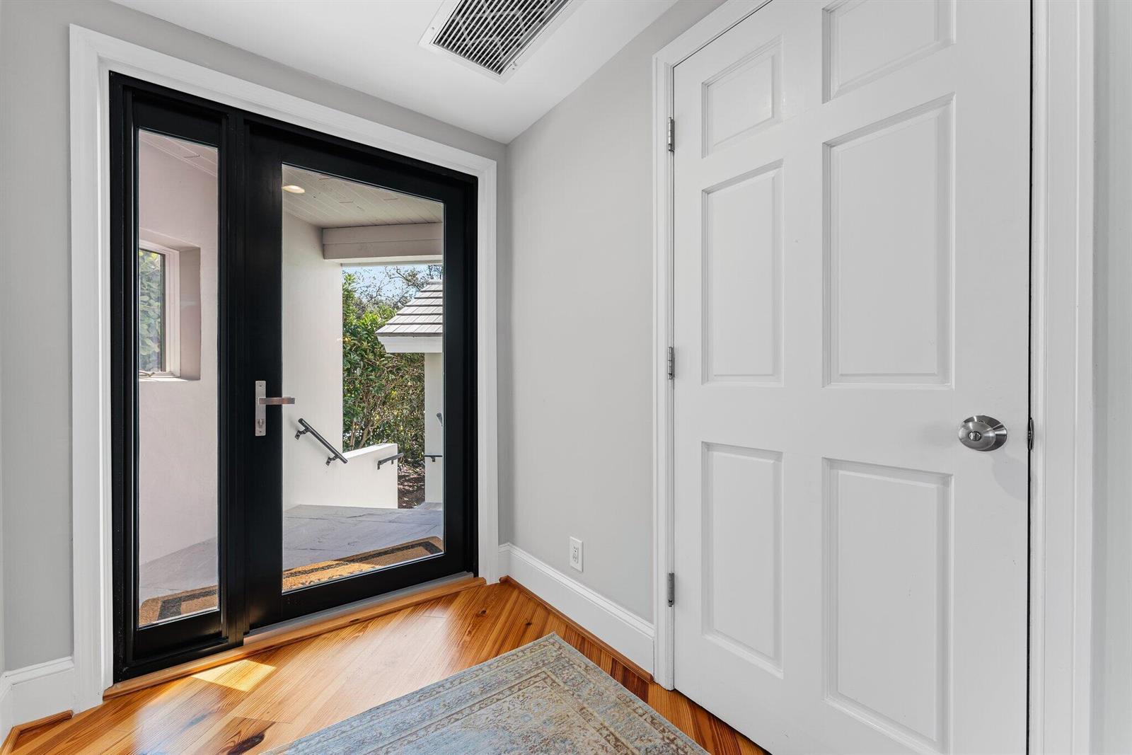 An entryway features a black-framed glass door, a white interior door, and hardwood flooring — 18760 SE Pineneedle Lane, Jupiter FL 33469, JUPITER, FL