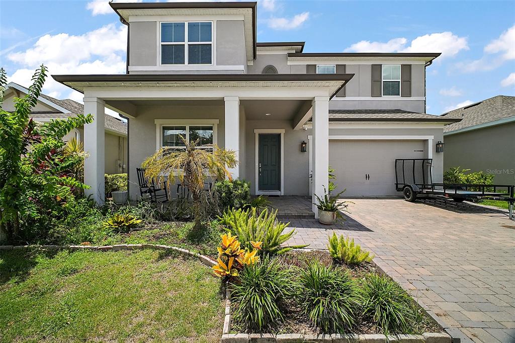 A two-story suburban house with a gray exterior, covered front porch, and paved driveway — 9153 CARMELA AVENUE, DAVENPORT, FL