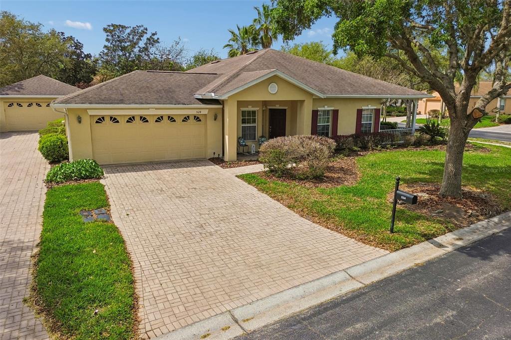 A single-story yellow house with a brick paver driveway and a two-car garage — 524 GLENDORA ROAD, KISSIMMEE, FL