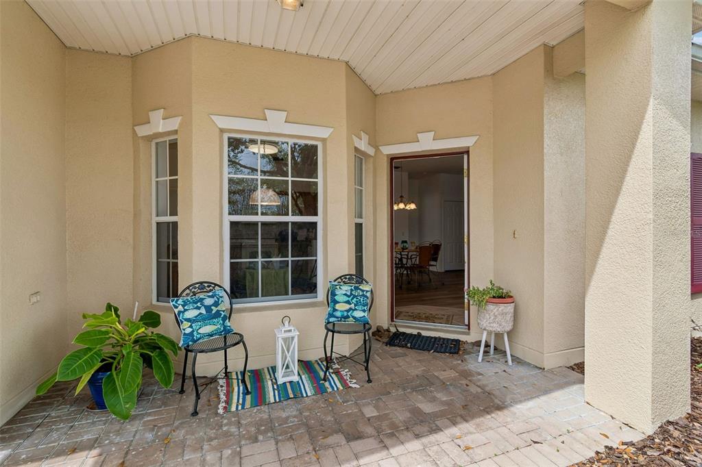 A paved front porch features two chairs, a small rug, a potted plant, and an entryway — 524 GLENDORA ROAD, KISSIMMEE, FL