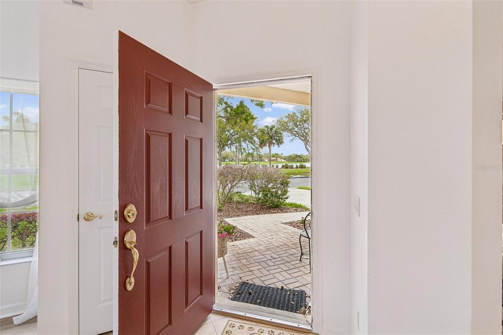 An open red front door reveals a brick walkway and a view of outdoor landscaping — 524 GLENDORA ROAD, KISSIMMEE, FL
