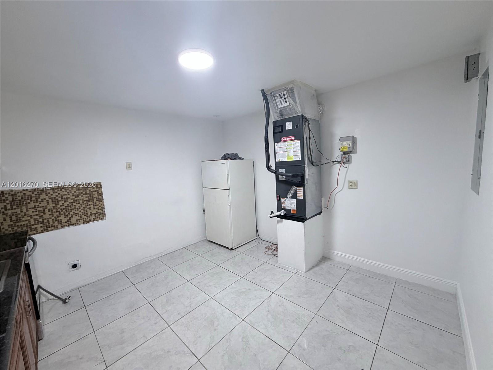 A kitchen area features light tile flooring, a refrigerator, and an exposed HVAC unit — 717 NE 1st St, Hallandale Beach FL 33009, HALLANDALE BEACH, FL