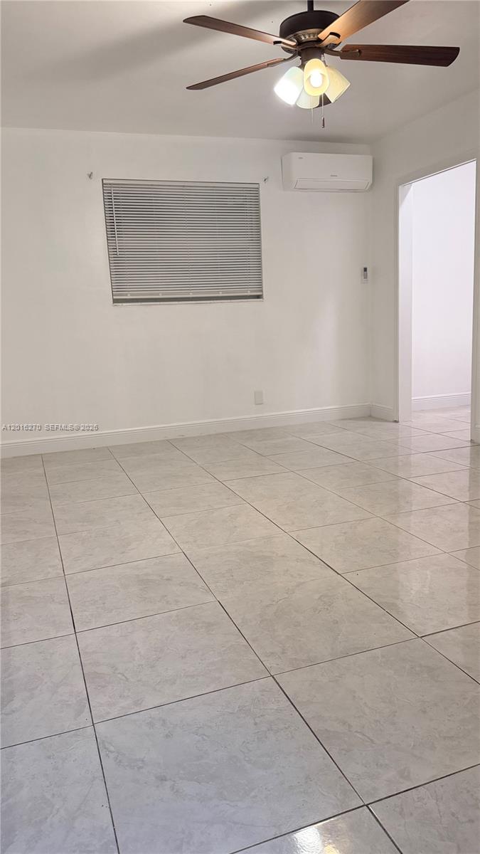 A room with white walls, light-colored tile flooring, a ceiling fan, and a wall-mounted air conditioner — 717 NE 1st St, Hallandale Beach FL 33009, HALLANDALE BEACH, FL