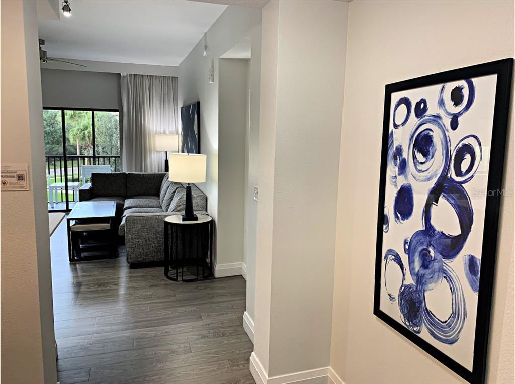 A view from a hallway looking into a living room with gray flooring and furniture — 14501 GROVE RESORT AVENUE UNIT 3231, WINTER GARDEN, FL
