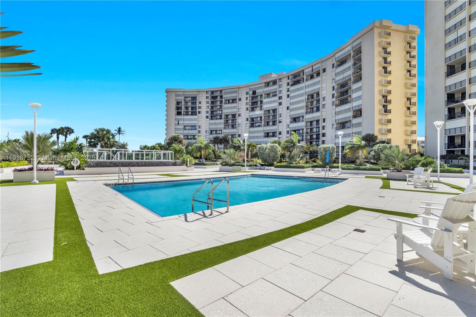 An outdoor swimming pool surrounded by a paved deck and artificial grass near a building — 200 Ocean Trail Way # 609, Jupiter FL 33477, JUPITER, FL