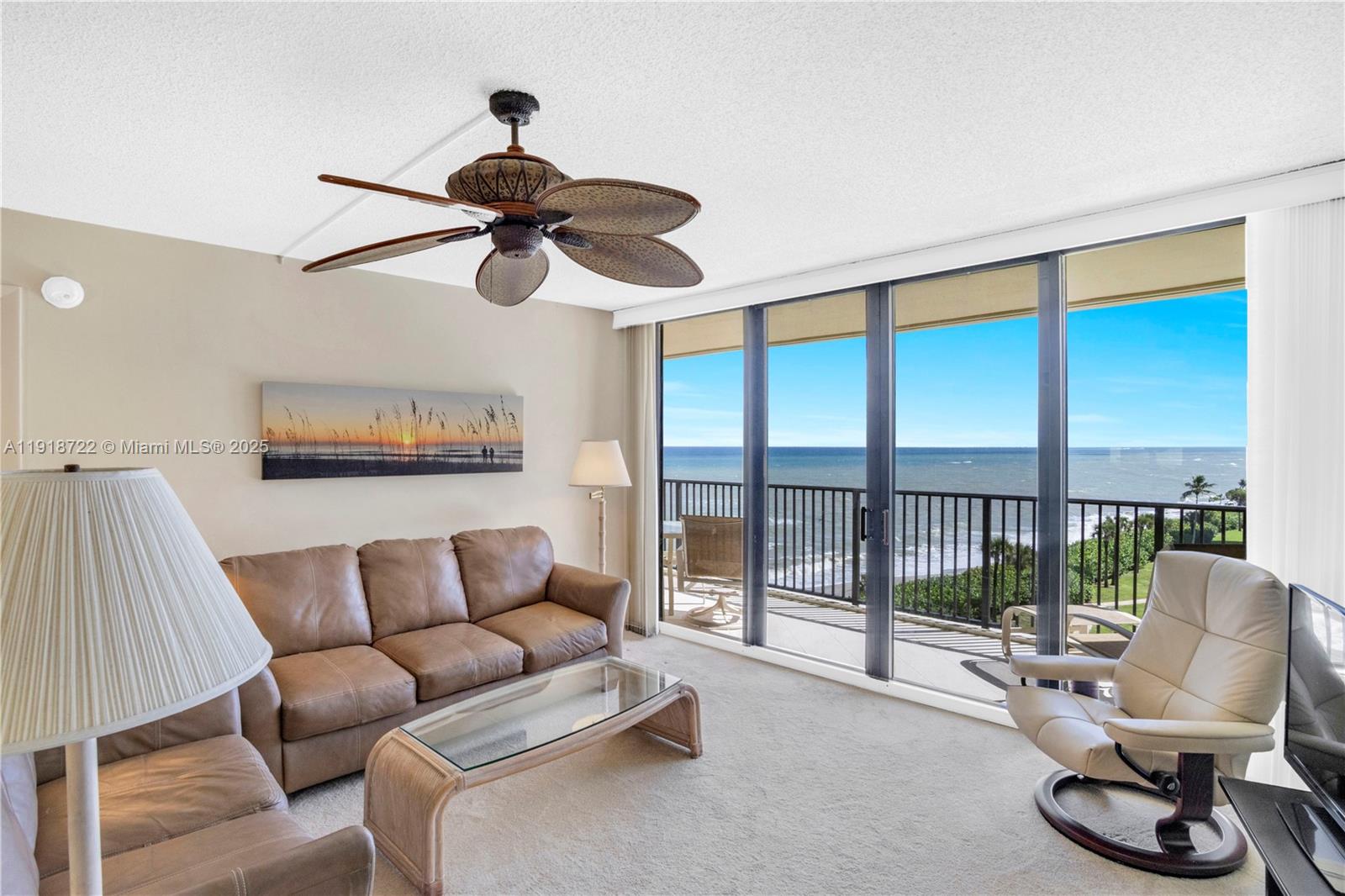 A living room features a leather sofa, glass coffee table, ceiling fan, and oceanfront balcony — 200 Ocean Trail Way # 609, Jupiter FL 33477, JUPITER, FL