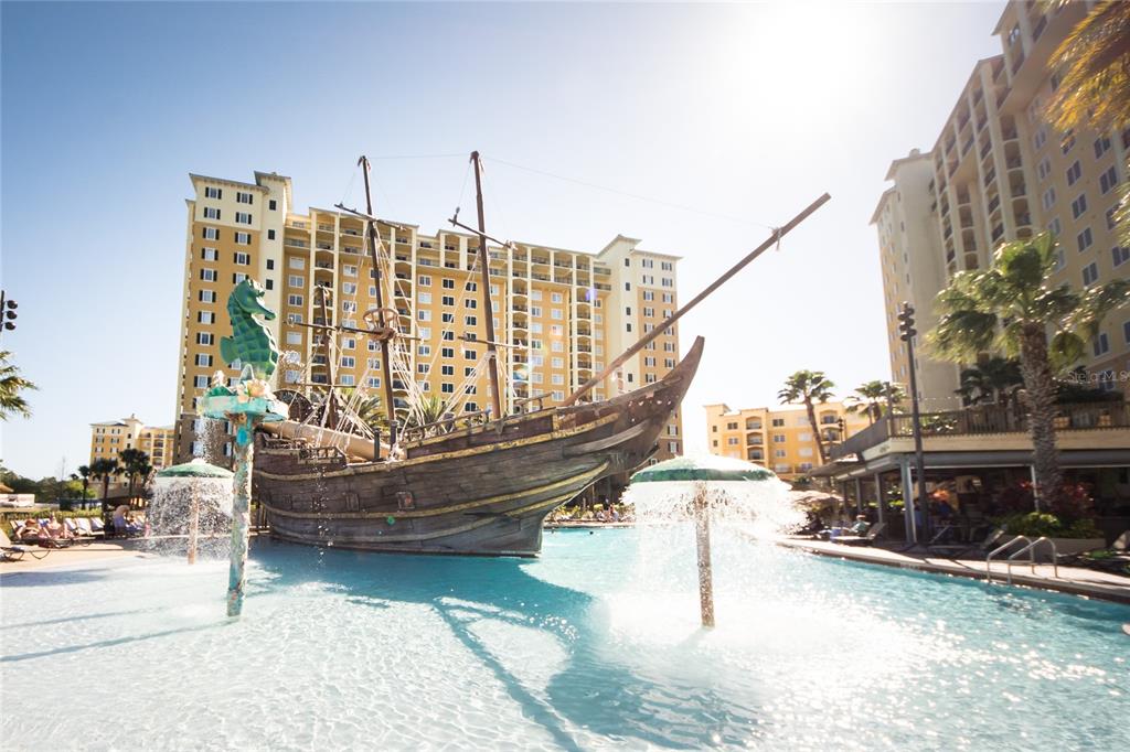 A large pirate ship play structure sits in the center of a resort swimming pool — 8112 POINCIANA BOULEVARD UNIT 1802, ORLANDO, FL