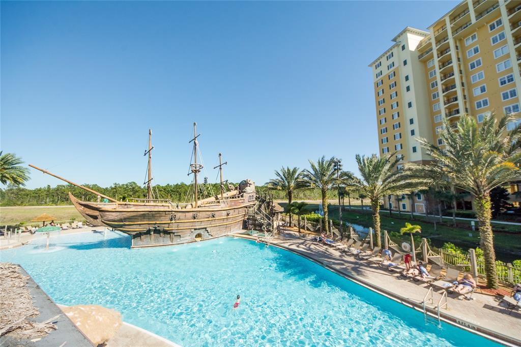 A swimming pool features a large pirate ship structure next to a tall hotel building — 8112 POINCIANA BOULEVARD UNIT 1802, ORLANDO, FL