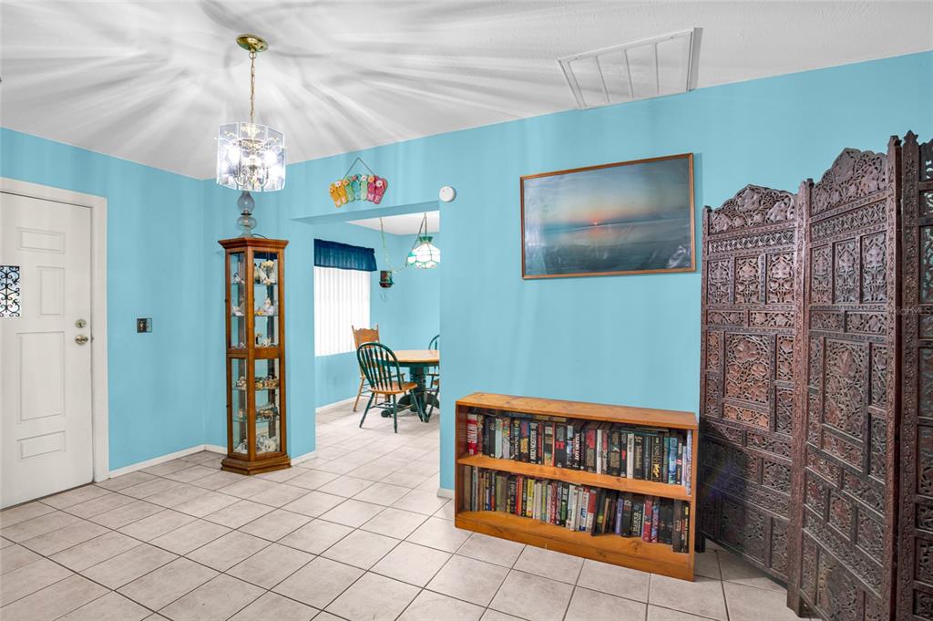 A room with light blue walls, tile flooring, a wooden bookshelf, and a decorative room divider — 104 LUDWIG AVENUE, CRESCENT CITY, FL