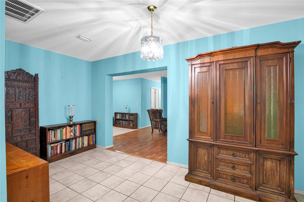 A room with light blue walls, tile flooring, a large wooden armoire, and a bookshelf — 104 LUDWIG AVENUE, CRESCENT CITY, FL