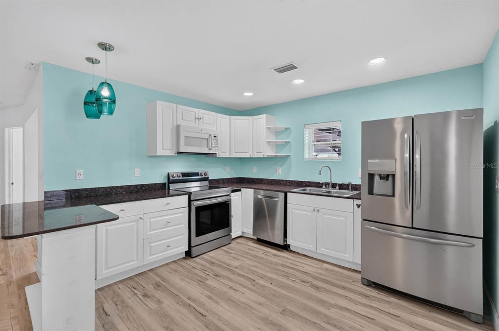 A kitchen with white cabinets, dark countertops, stainless steel appliances, and light blue walls — 2005 SCHULTE AVENUE, DAYTONA BEACH, FL