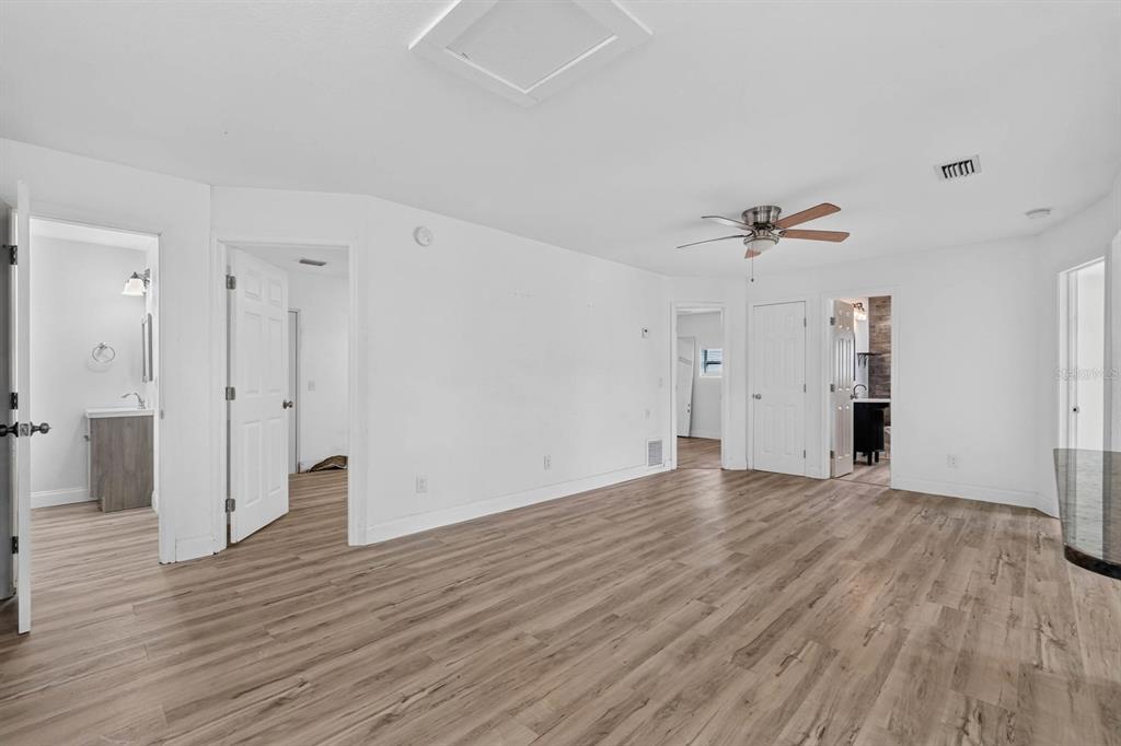 A bright room with light wood-look flooring, white walls, a ceiling fan, and multiple doorways — 2005 SCHULTE AVENUE, DAYTONA BEACH, FL