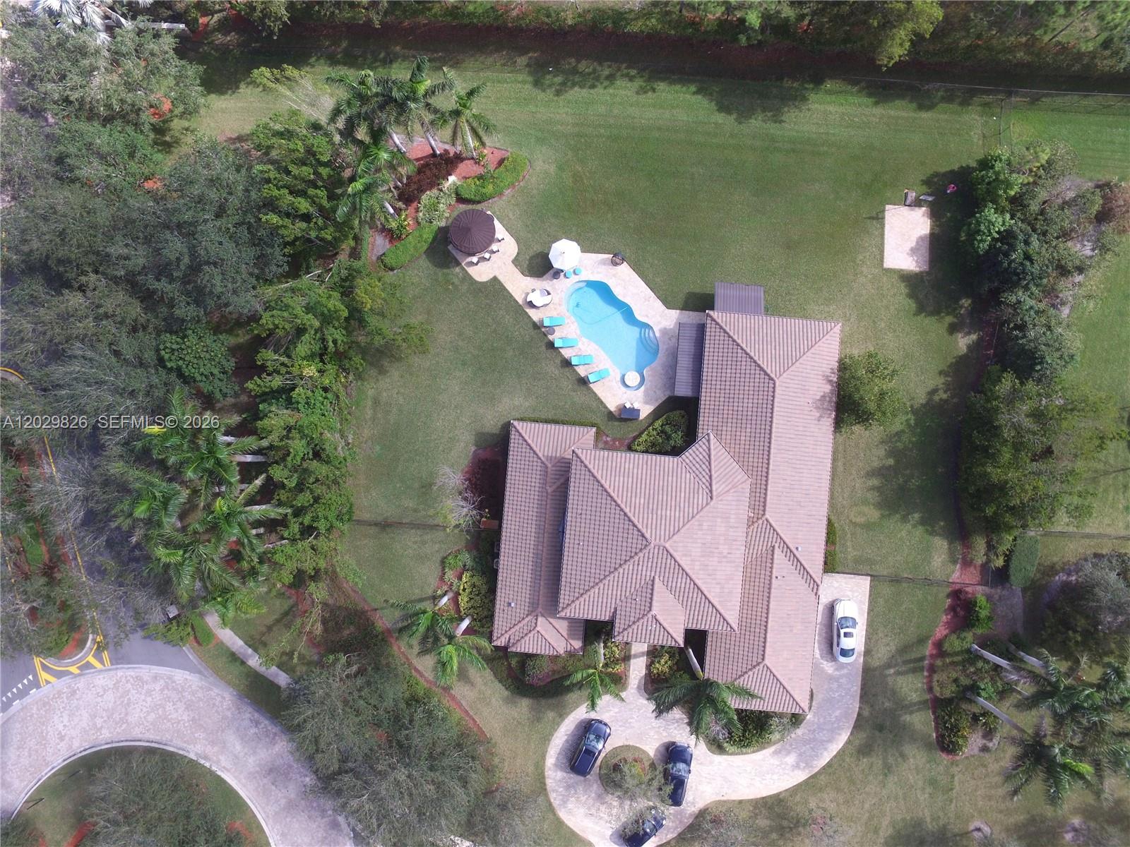 An aerial view shows a house with a tiled roof, swimming pool, and circular driveway — 2750 E Jockey Cir E, Davie FL 33330, DAVIE, FL