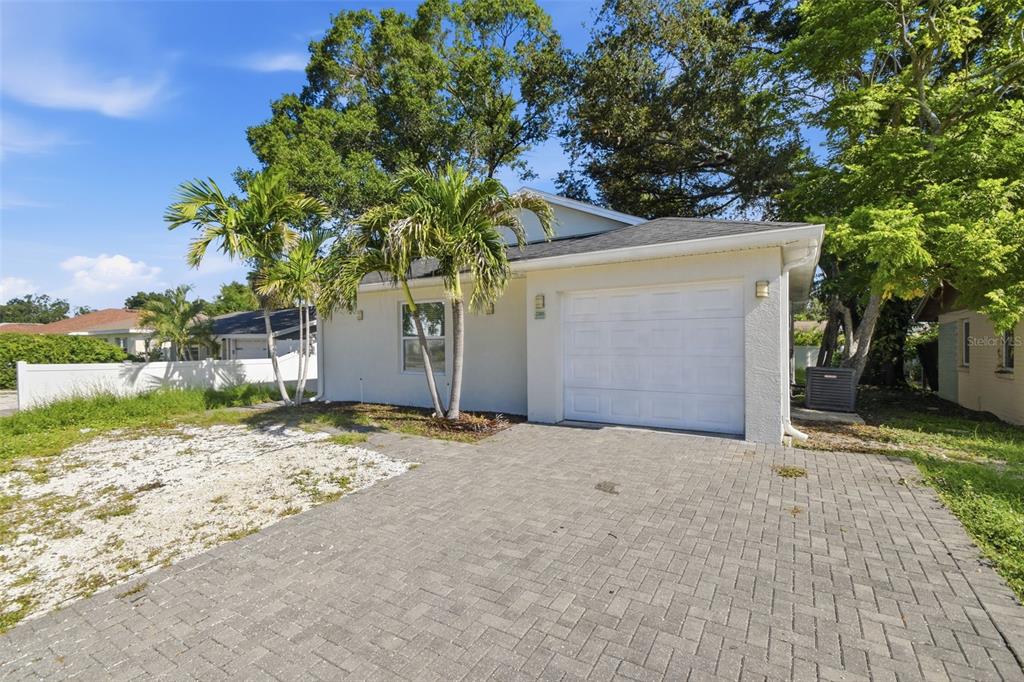 A single-story house with a white garage, paved driveway, and palm trees in the front yard — 2303 BAHIA VISTA STREET, SARASOTA, FL