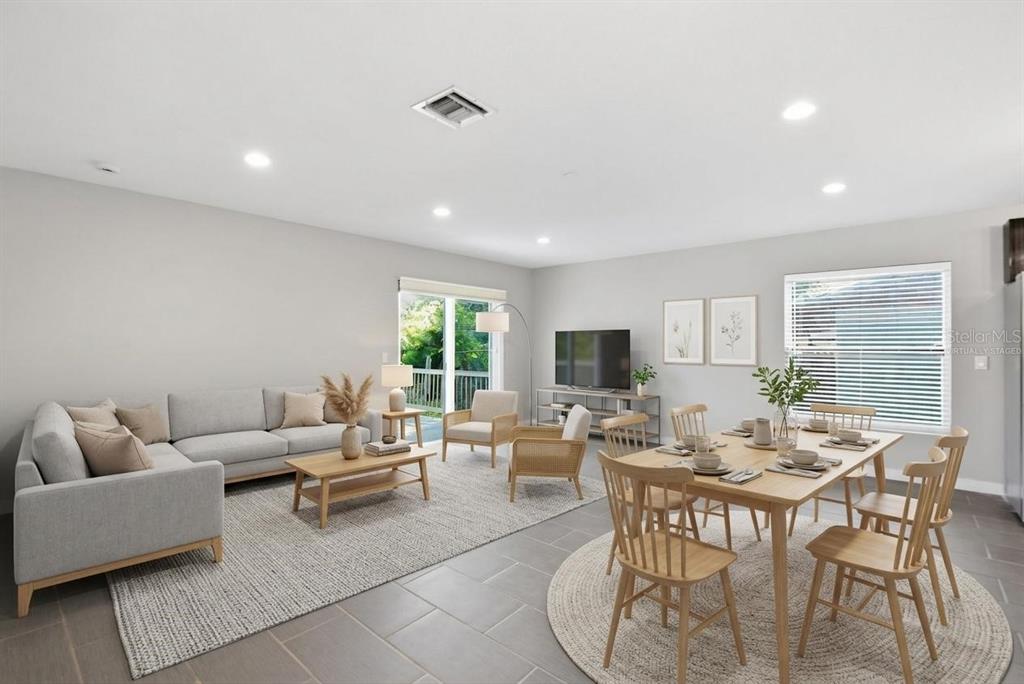 A living and dining area with gray tile floors, light-colored furniture, and large windows — 2303 BAHIA VISTA STREET, SARASOTA, FL