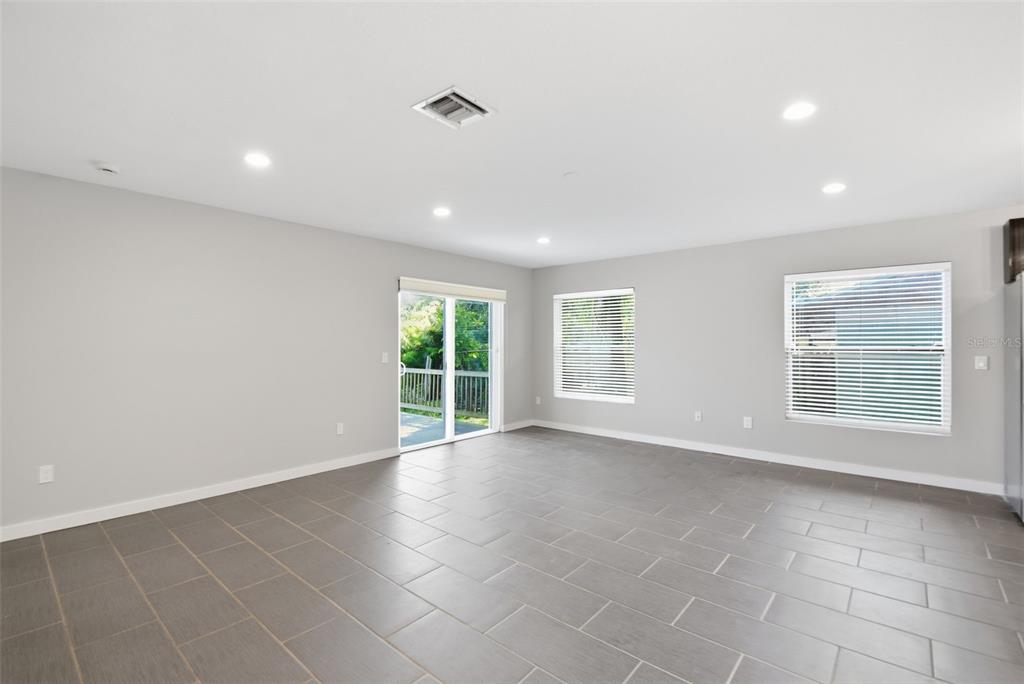 A bright, empty room features gray tile flooring, recessed lighting, and a sliding glass door — 2303 BAHIA VISTA STREET, SARASOTA, FL