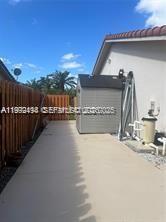 A concrete side yard features a small storage shed and pool equipment against a house — 15751 SW 141st Ct, Miami FL 33177, MIAMI, FL