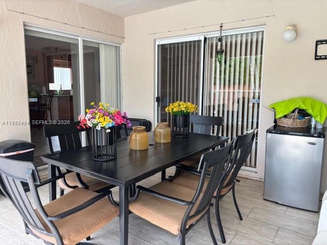 A covered patio features a black dining table with six chairs and a small refrigerator — 15751 SW 141st Ct, Miami FL 33177, MIAMI, FL