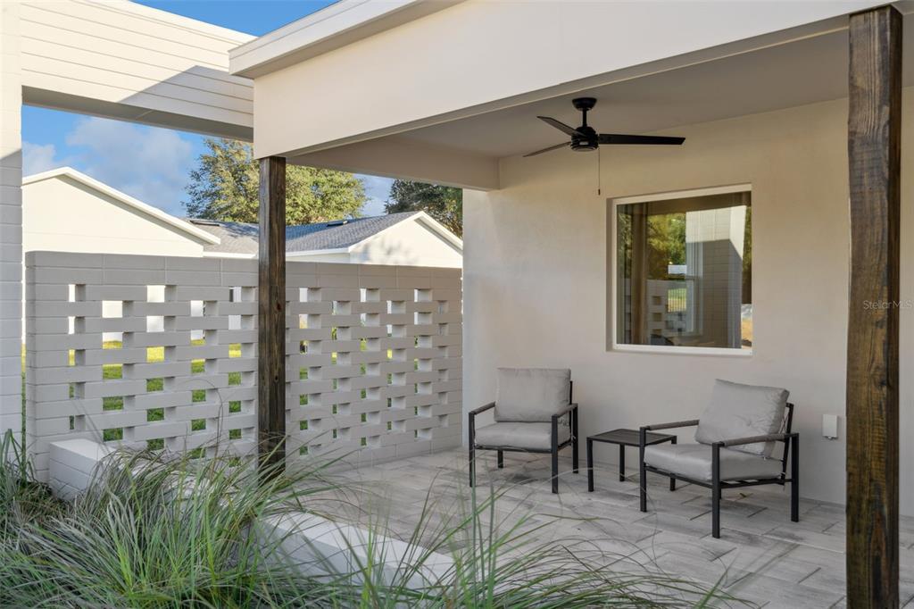 A covered patio features a decorative white brick privacy wall, two chairs, and a ceiling fan — 450 SKYFIELD COURT, LADY LAKE, FL