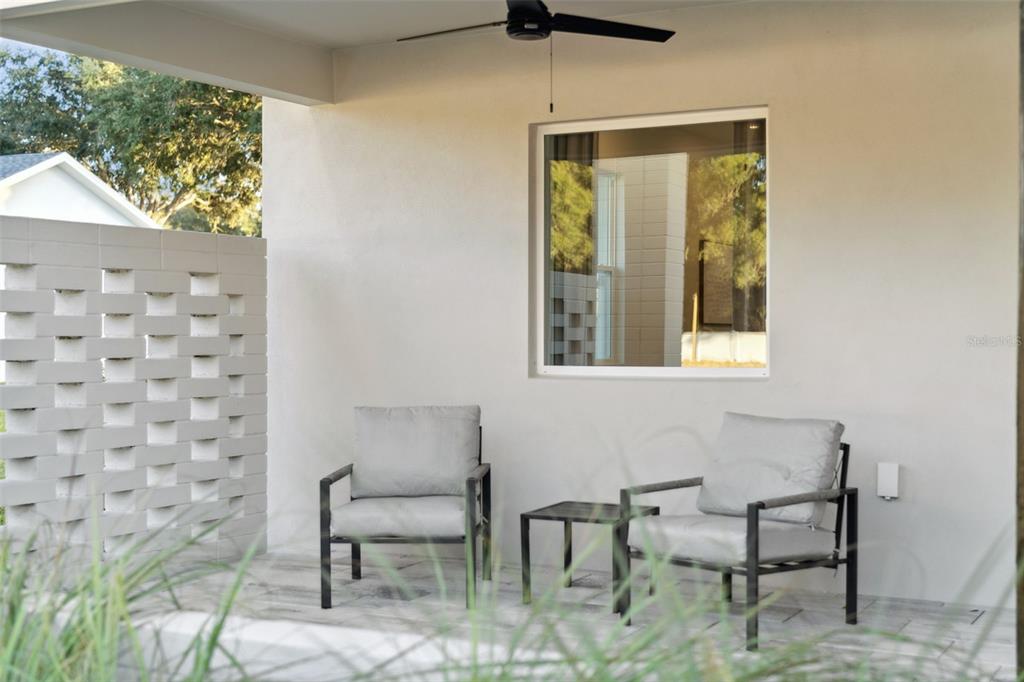 A covered patio features two gray chairs, a small table, and a decorative brick wall — 450 SKYFIELD COURT, LADY LAKE, FL